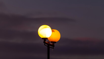 Lit street lamp with icicles in close-up on the background of the night sky in winter.