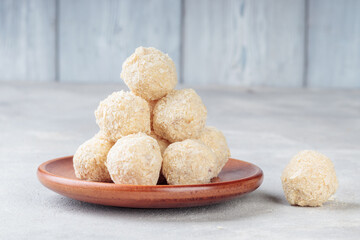 Close-up view of Healthy raw paleo energy coconut balls in wooden plate.
