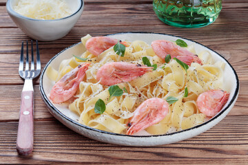 Pasta fettuccine with shrimp in rustic plate on wooden background. Selective focus.
