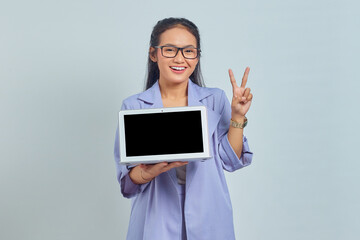 Portrait of smiling young Asian woman showing blank laptop screen and  and showing peace sign isolated on white background
