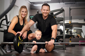 Family at the gym. Young parents with a small child train in the gym.