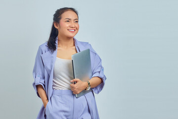 Portrait of smiling young Asian woman holding a laptop and looking aside isolated on white background