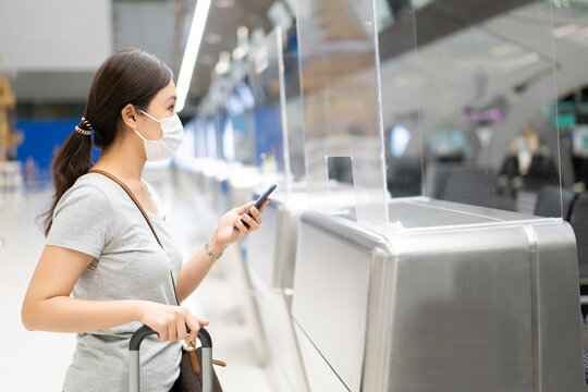 Happy Asian young woman wearing a protective face mask in the airport.