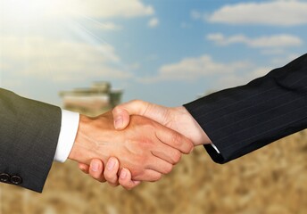 Two farmers shaking hands in field during wheat harvest