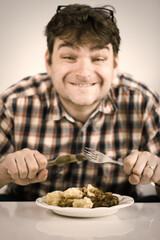 Man eating his lunch made of baked rabbit meat and gnocchi