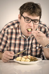 Man eating his lunch made of baked rabbit meat and gnocchi