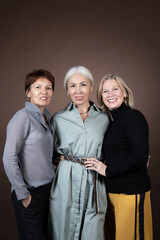 Portrait of elegant mature women posing together at camera against the grey background
