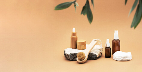Obraz na płótnie Canvas Blank amber glass and bamboo essential oil bottles with pipette, glass spray bottle and bamboo jar on natural stone podium. Organic spa cosmetic beauty product mock up.