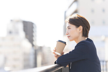 屋上でコーヒーを飲んで休憩するビジネスウーマン
