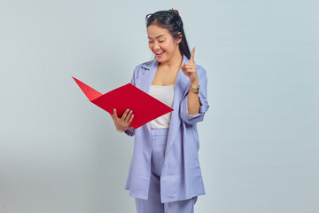 Obraz premium Portrait of cheerful young Asian business woman holding document folder and gets brilliant idea in mind isolted on purple background