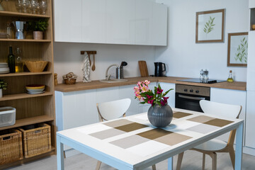 Image of beautiful flowers in vase on the table in modern kitchen at home