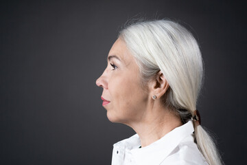 Naklejka premium Side view of mature woman with long white hair looking away isolated on grey background