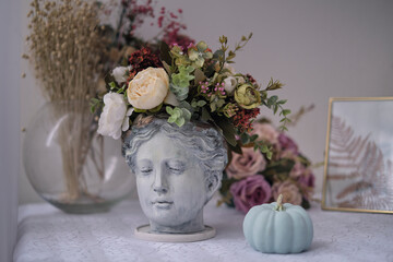 table by the window with interior details antique bust of Venus with flowers instead of hair