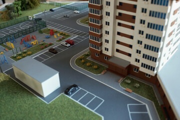 Layout of skyscraper surrounded by yard with playground, football ground, parking with cars and lawns with flowers and trees