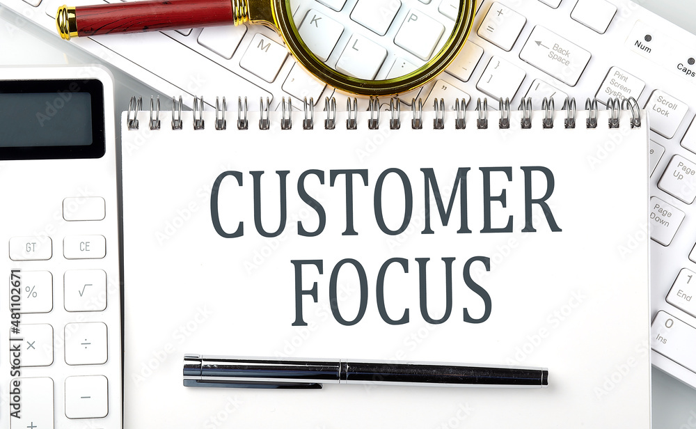 Poster customer focus text on notepad with calculator and keyboard,business concept