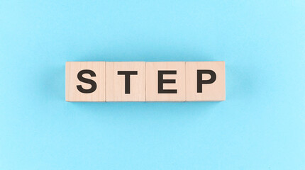 Wooden cube block with text STEP on the blue background