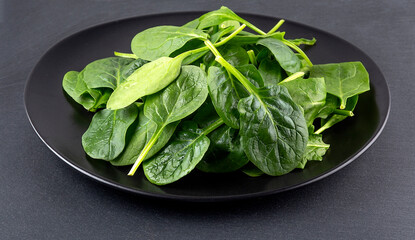 Spinach in black plate on black granite backrgounds.