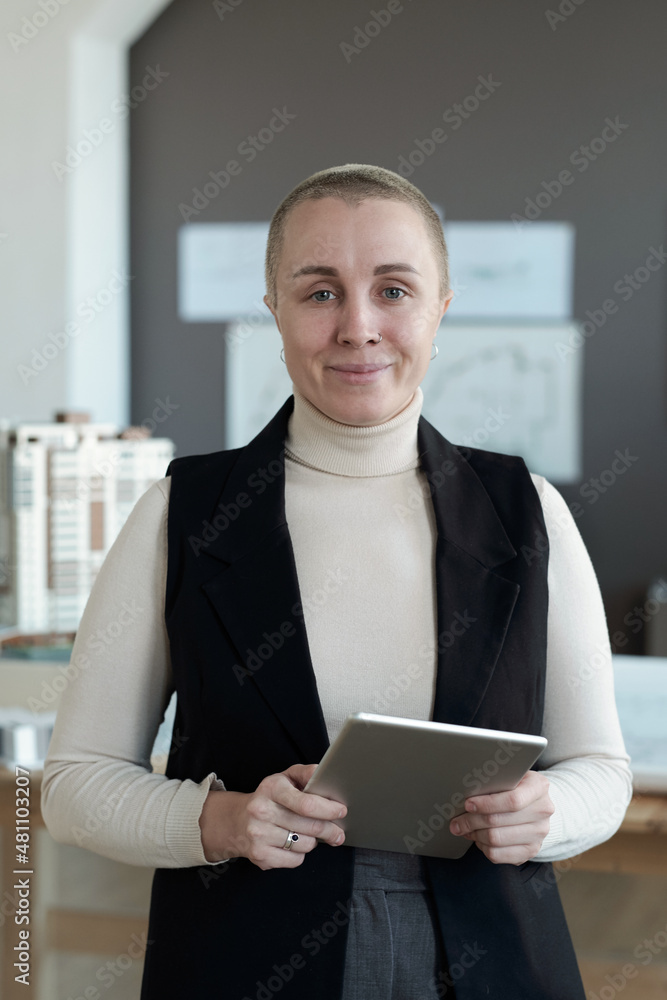 Poster Happy female architect with digital tablet looking at you while standing in front of camera in office environment