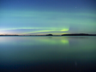 Northern lights dancing over calm lake in north of Sweden.