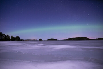 Fototapeta na wymiar Northern light dancing over frozen lake in north of Sweden,