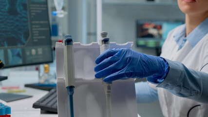 Close up of scientific micropipette on laboratory desk used by biotechnology specialist in lab coat...