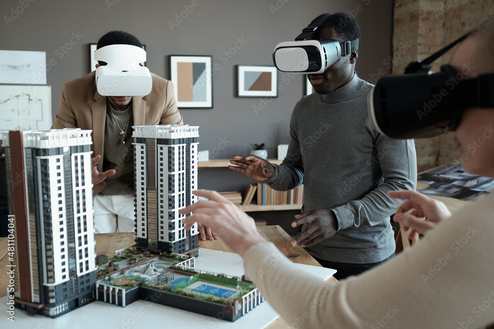 Poster Group of architects in vr headsets standing around table with house layout during presentation of new block of flats