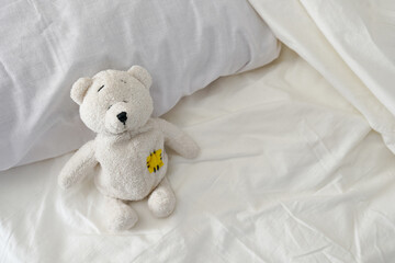 Toy Teddy Bear sitting on white bed