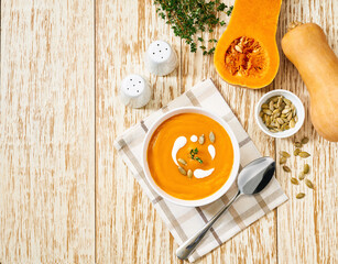 Bowl with pumpkin soup or butternut squash soup on a white wooden table, copy space for text.