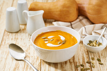 Bowl of homemade soup with organic butternut squash with cream sauce, selective focus.