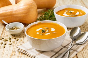 Two bowls of homemade soup with organic butternut squash with pumpkin seeds, selective focus.