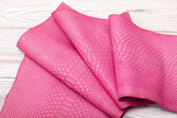 pink suede dyed genuine natural python leather on the wooden table	
