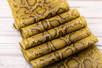 brown khaki dyed folded natural genuine python leather on the wooden table	