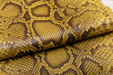 brown khaki dyed folded natural genuine python leather on the wooden table	