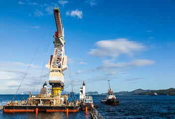 Shipment of a large floating crane by sea tugs on a semi-submersible transport vessel for its...