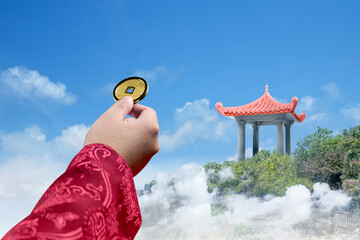 Hand holding golden Chinese coin with park background