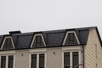 The roof of the house is made of red metal tiles, a beautiful large chimney