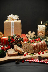 Traditional French terrine covered with bacon on dark wooden background with Christmas decorations