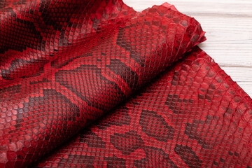 red spotted dyed folded natural genuine python leather on the wooden table	