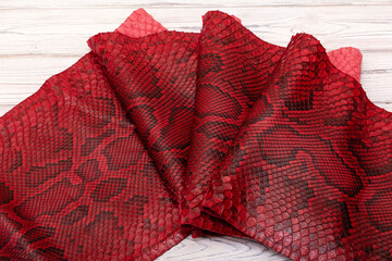 red spotted dyed folded natural genuine python leather on the wooden table	