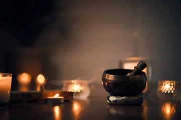 Selbstklebende Fototapeten A close-up of a Tibetan bowl with blurred background candles and also a plant. Photo taken in a spiritual and mystical tone after a yoga session. © Victor Santacruz
