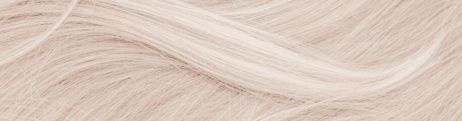Background hair closeup. Female long blond hair close-up as a background. Beautifully laid wavy shiny curls. Hair coloring. Hairdressing procedures. Copy space with space for text.
