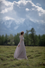 a girl in a royal image, a girl walks against the backdrop of mountains, a girl in a gray dress