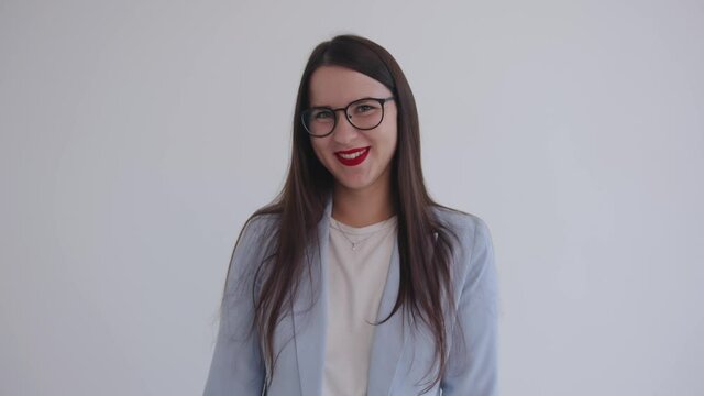 A confident young business woman stands on a white background and shows with gestures and her head that no