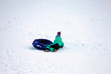 Child fell at riding on snow tube. Concept of tubing, safety during winter entertainment