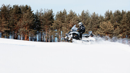 In deep snowdrift snowmobile rider driving fast. Riding with fun in white snow powder during...