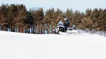 Fotobehang In deep snowdrift snowmobile rider driving fast. Riding with fun in white snow powder during backcountry tour. Extreme sport adventure, outdoor activity during winter holiday on ski mountain resort. © Tropical studio