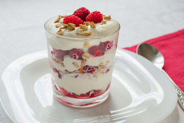 Traditional Scottish Cranachan dessert with toasted oats, fresh raspberries, cream and whisky in a glass close up.