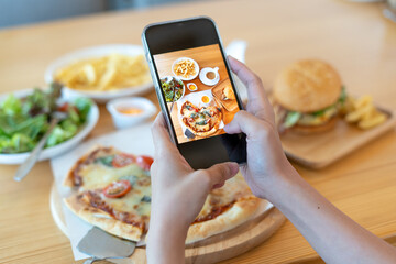 italian food. The restaurant owner takes a picture of the food on the table with a smartphone to post on a website. Online food delivery and ordering service