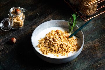 Delicious yogurt with granola and nuts served on dark table, closeup. Oatmeal granola. Baked granola with nuts. Healthy breakfast. Vegan granola.