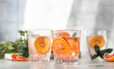 Cold refreshing drink with tonic, blood Sicilian oranges and ice, grey concrete background....